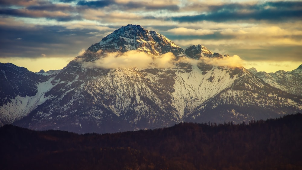 una montagna coperta di neve sotto un cielo nuvoloso