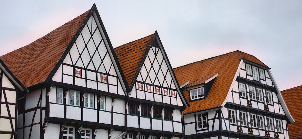 a row of white and black houses with red roofs