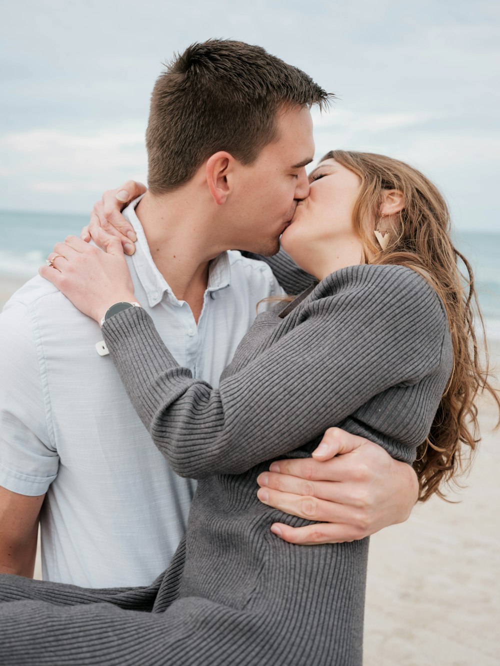 a man and a woman kissing on the beach
