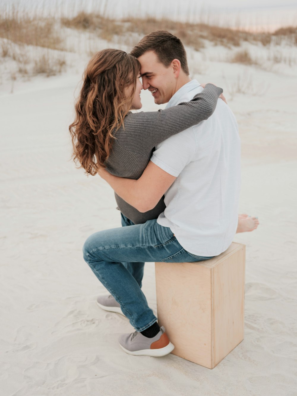 a man and woman sitting on a box in the sand