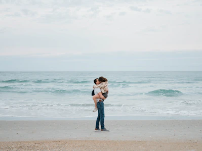 a woman holding a baby on the beach