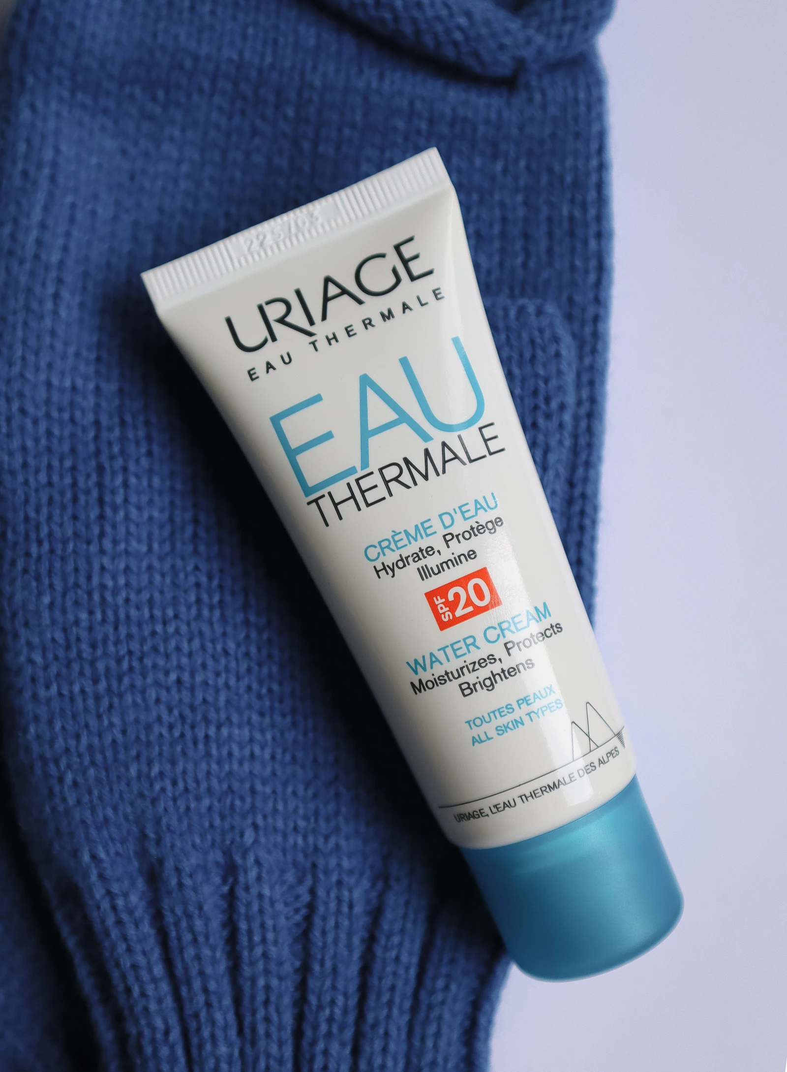 A tube of sunscreen resting on a knit blue sweater, representing a facial SPF comparison