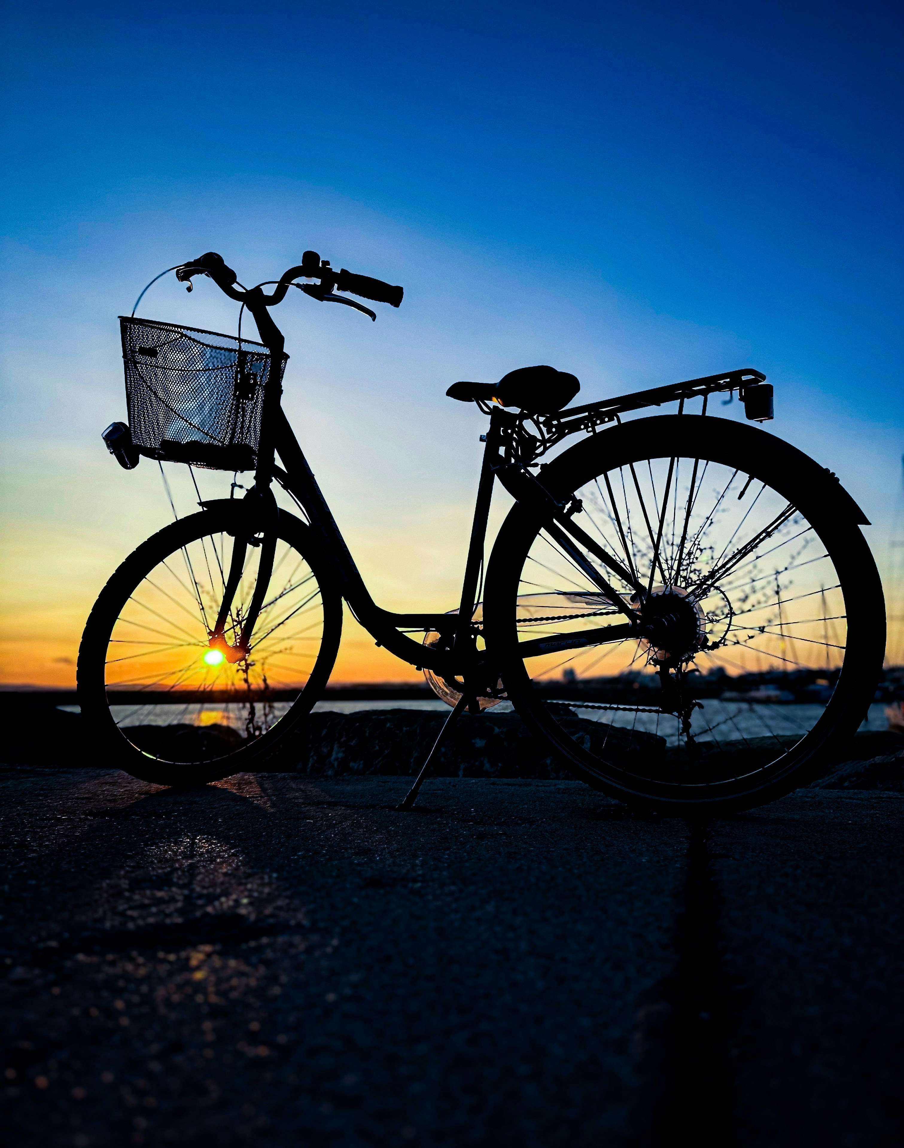 a bicycle parked on the beach at sunset
