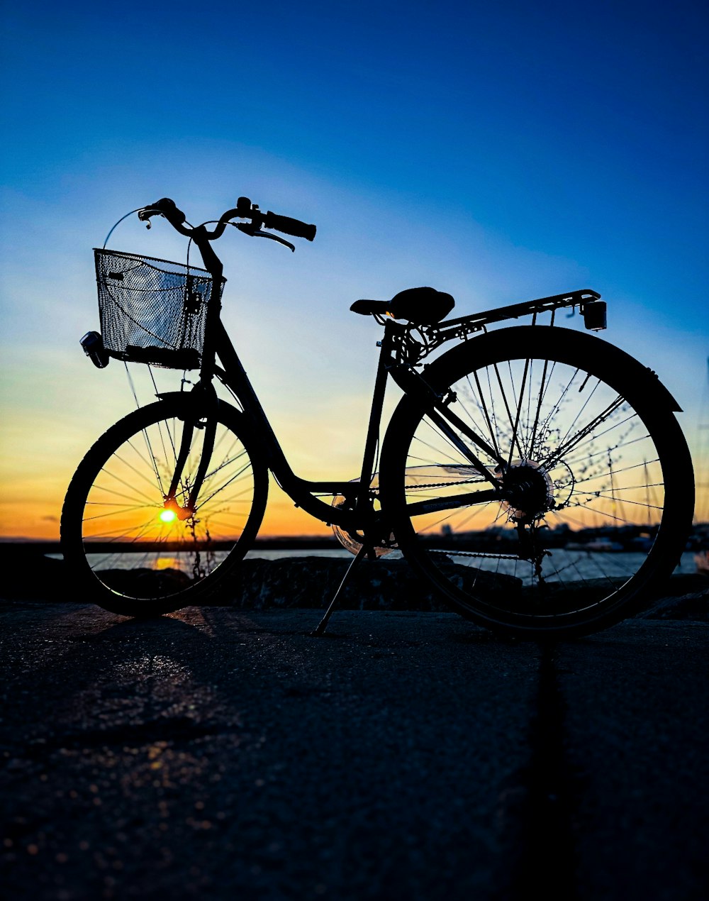 a bicycle parked on the beach at sunset