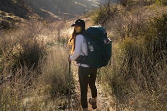 a woman with a backpack walking on a trail