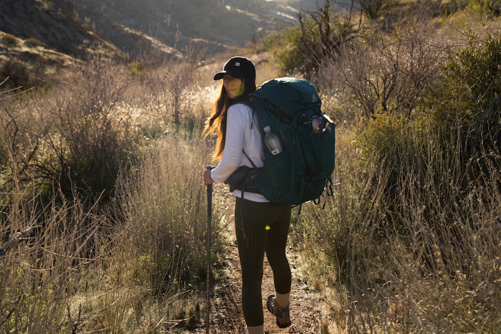 a woman with a backpack walking on a trail