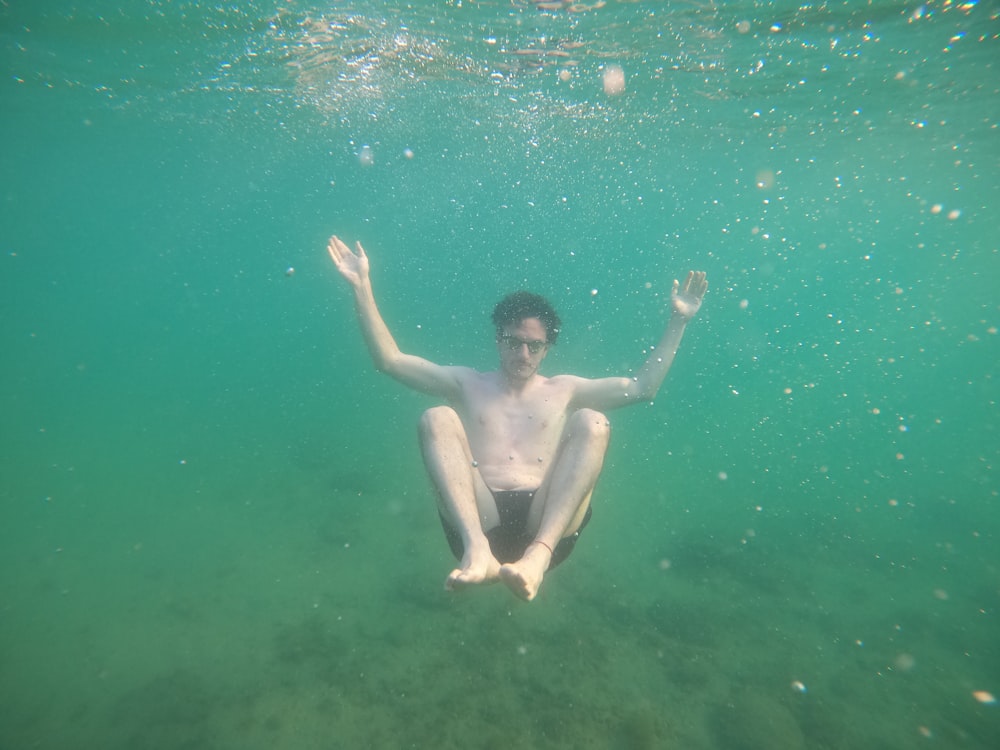 a man floating in the water with his hands up