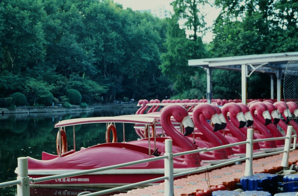 a row of red boats sitting on top of a lake