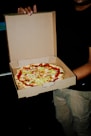 a man is holding a pizza in a box