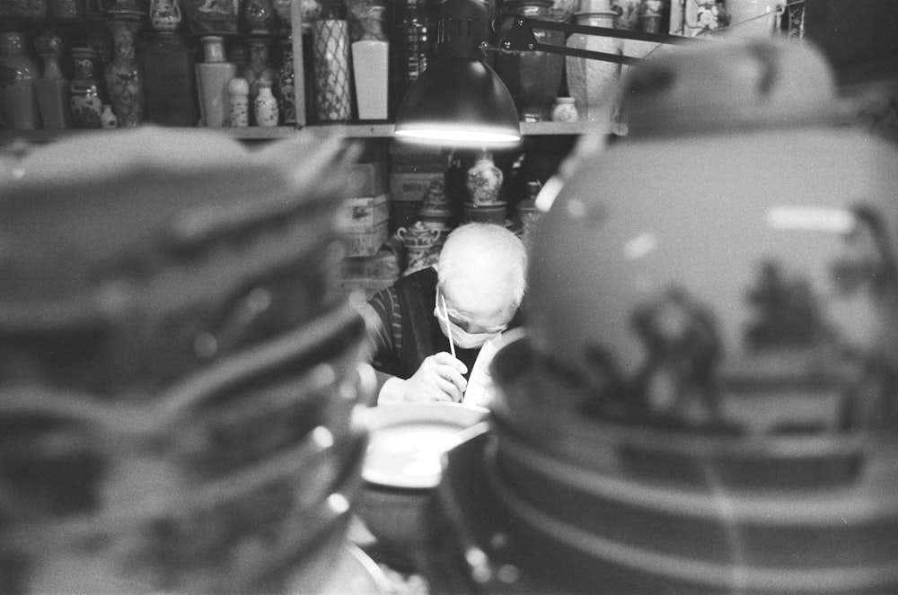 a black and white photo of a man writing in a shop