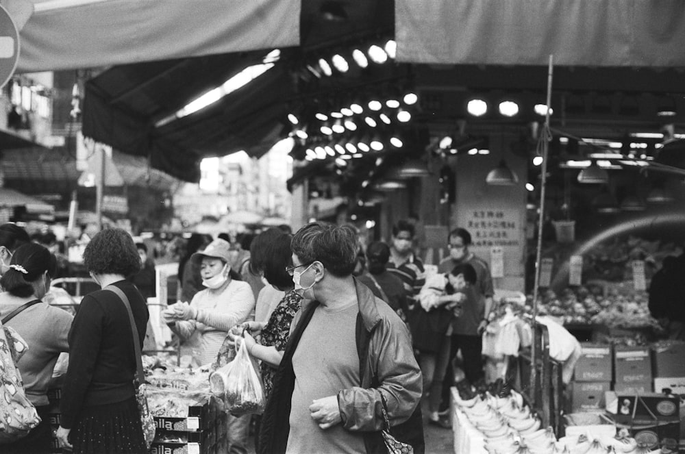 a black and white photo of people shopping in a market