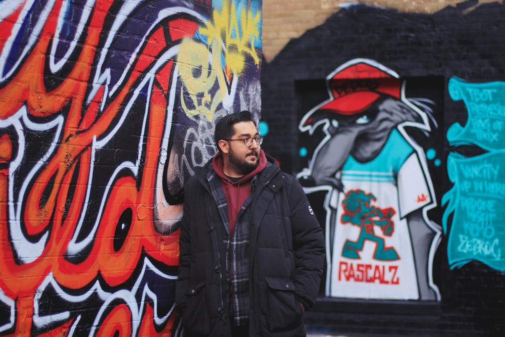 a man standing next to a wall covered in graffiti