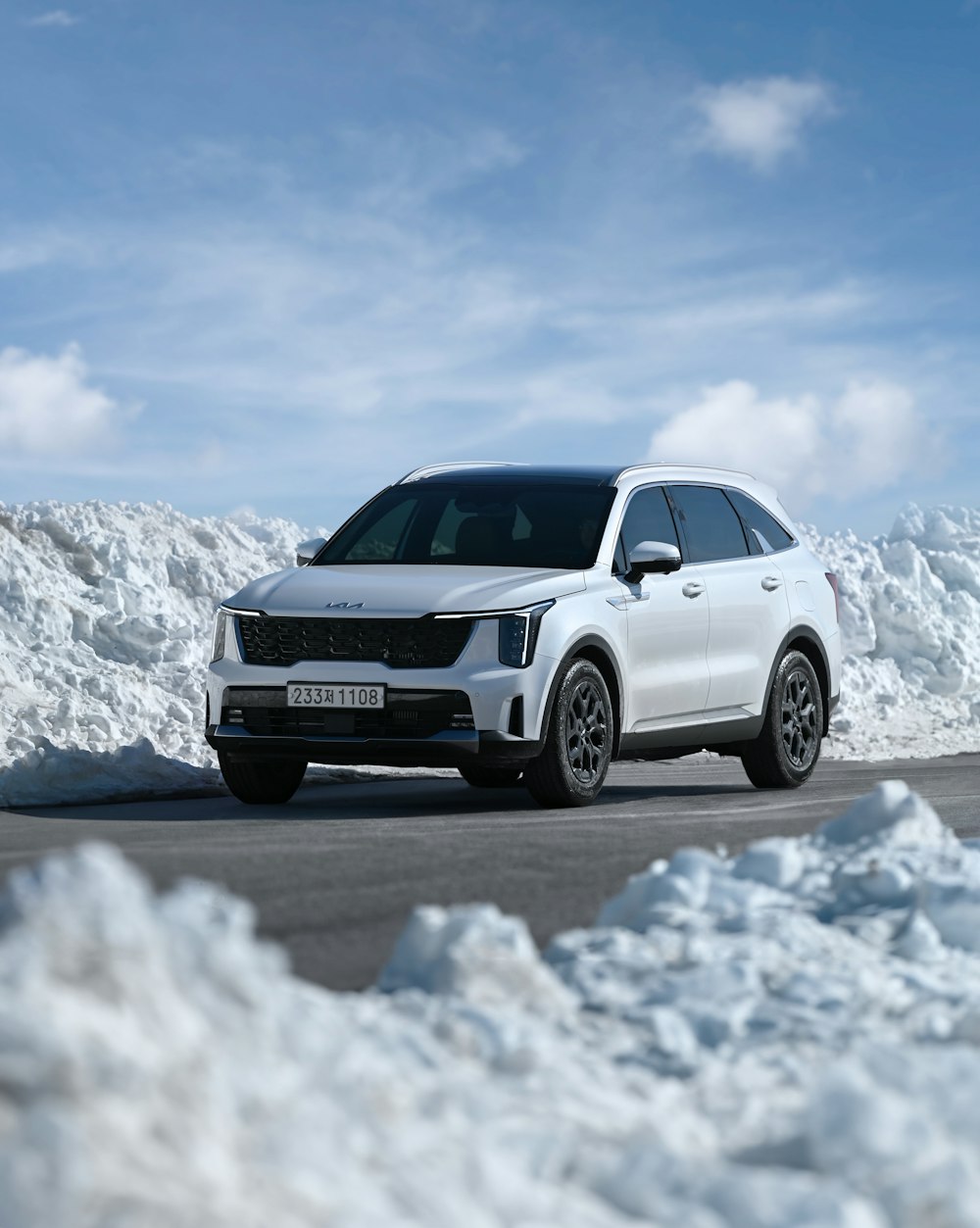 a white car driving down a road covered in snow