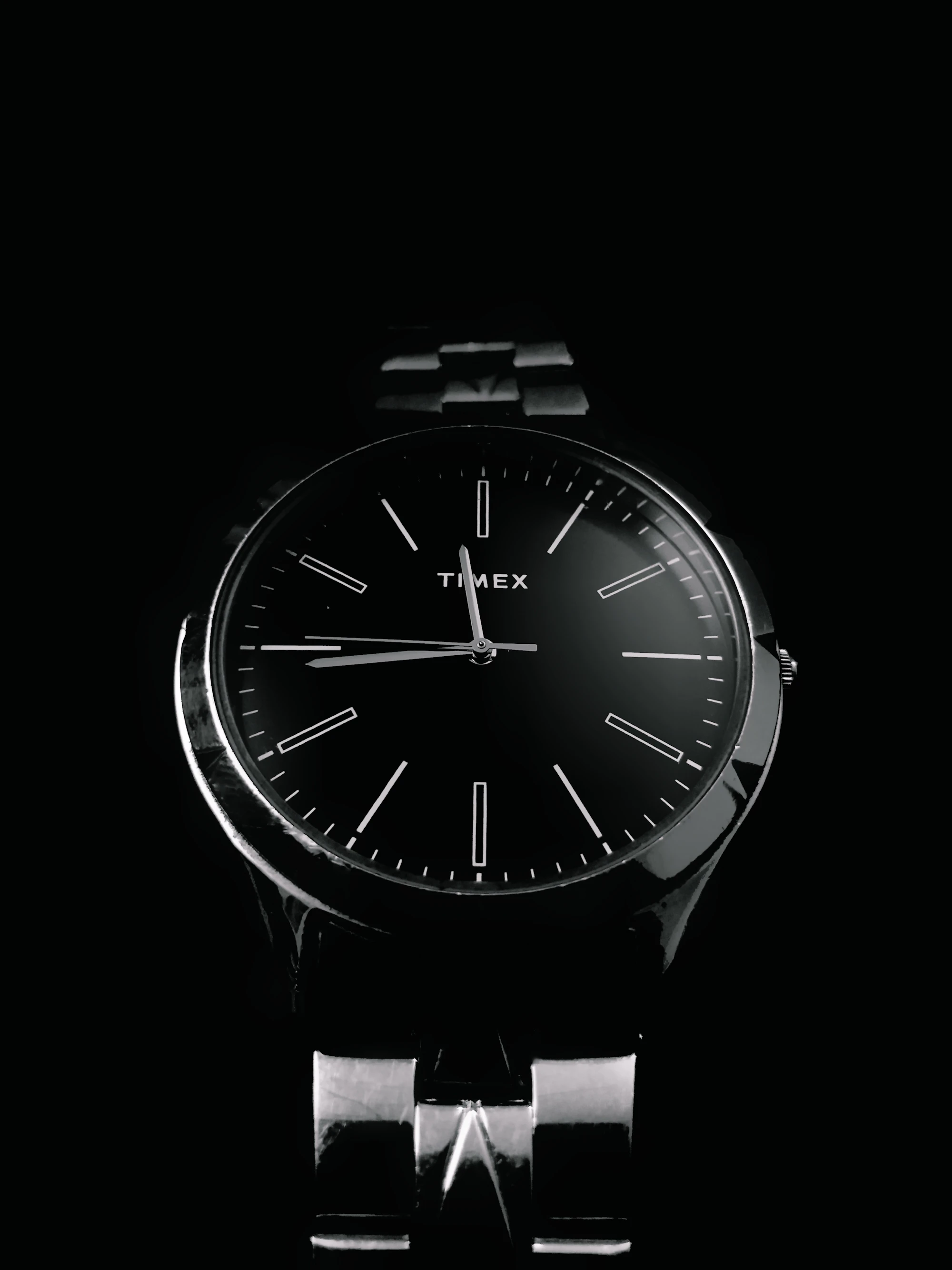 Close-up of a watch on a black background, showing steel case and strap texture