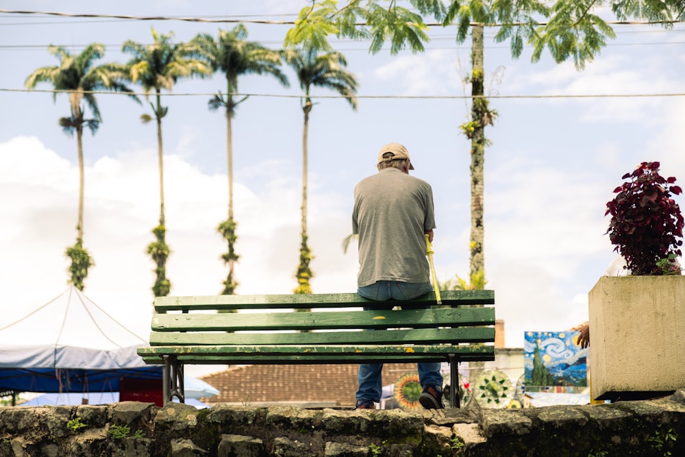 a man sitting on a bench next to a potted plant