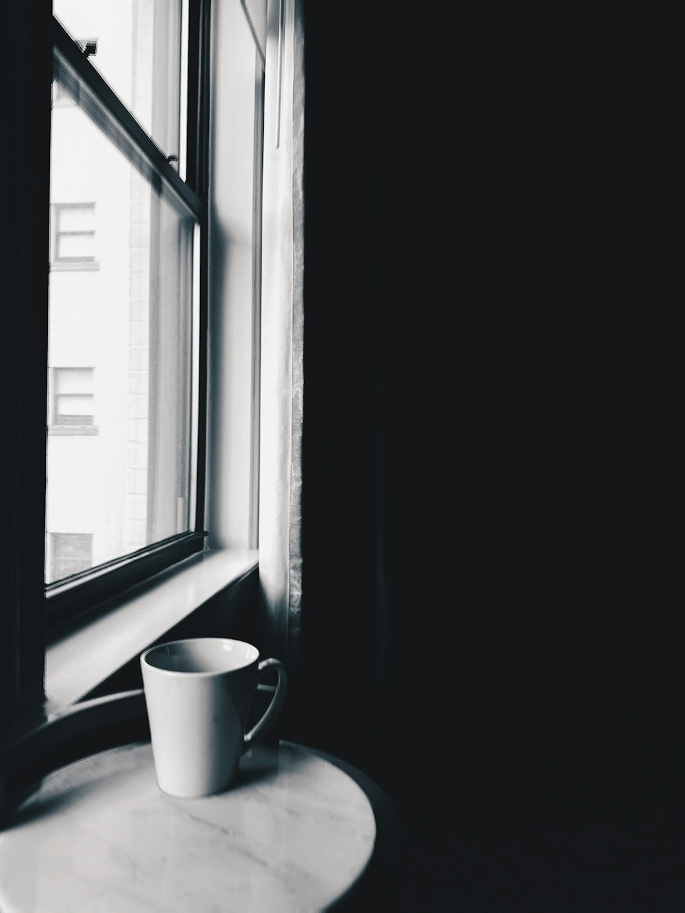una taza sentada en una mesa junto a una ventana