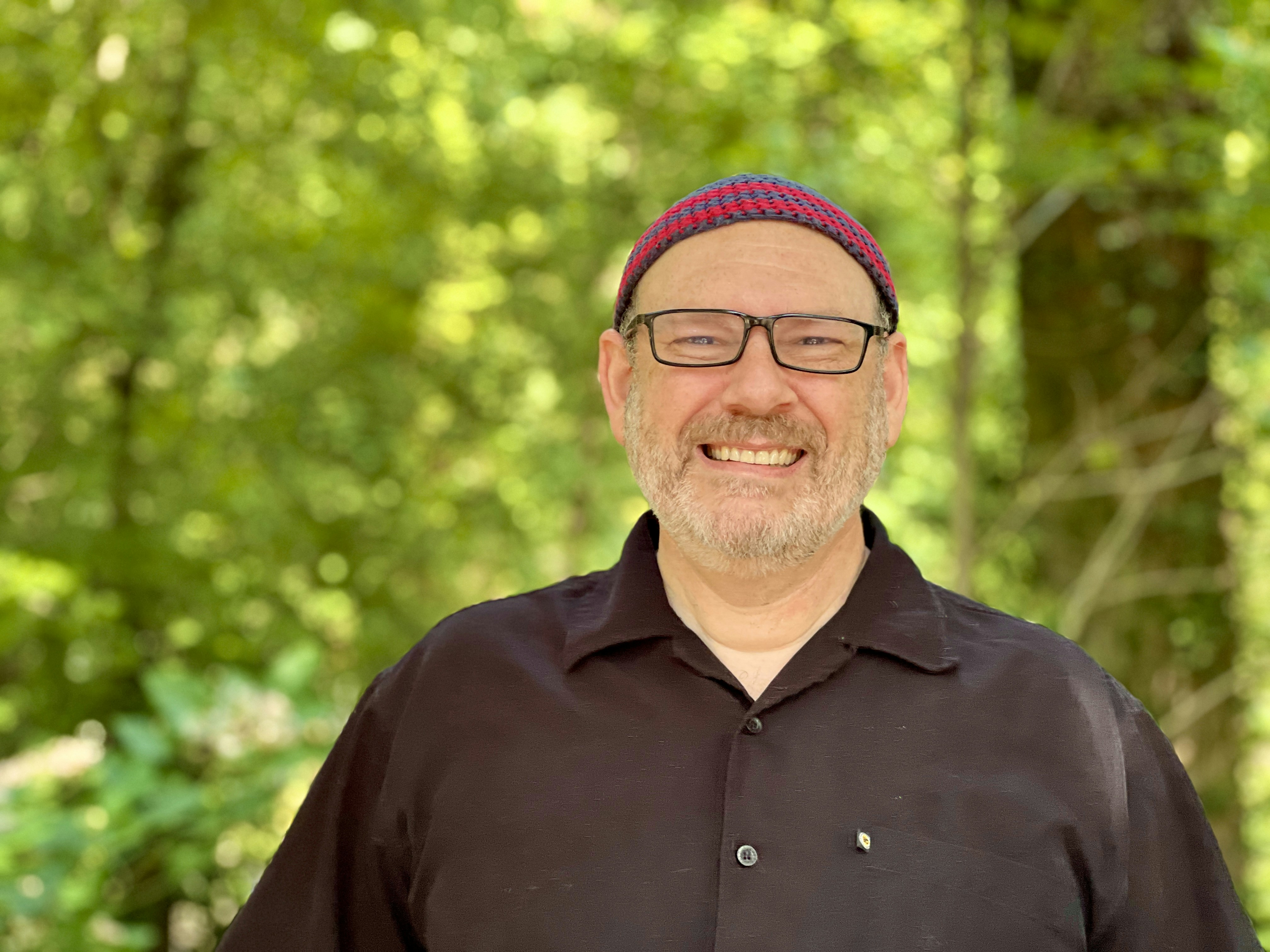 a man with glasses and a hat smiling