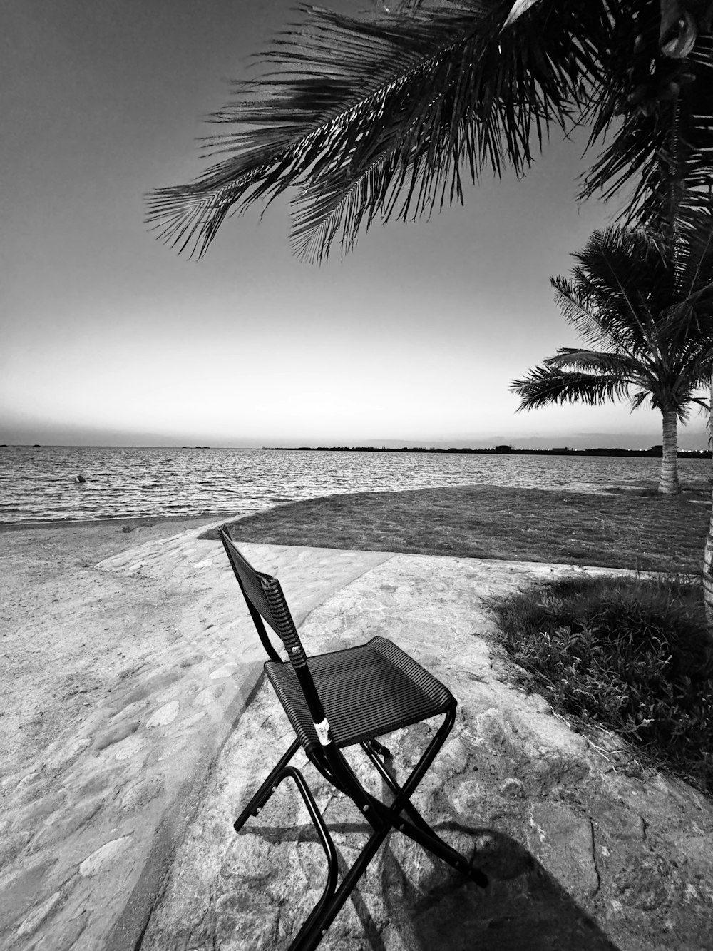 a black and white photo of a chair on a beach