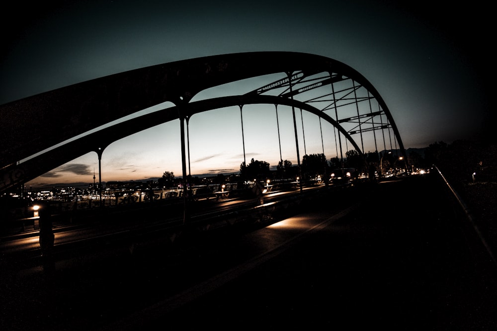 a bridge over a highway at night with lights on