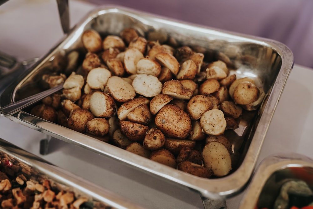 a metal tray filled with potatoes and nuts