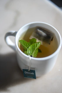 a cup of tea with a green leaf in it