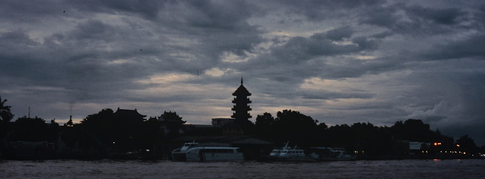a group of boats sitting on top of a river under a cloudy sky