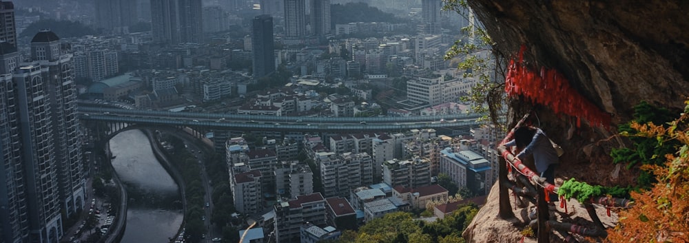 a man standing on top of a cliff next to a city