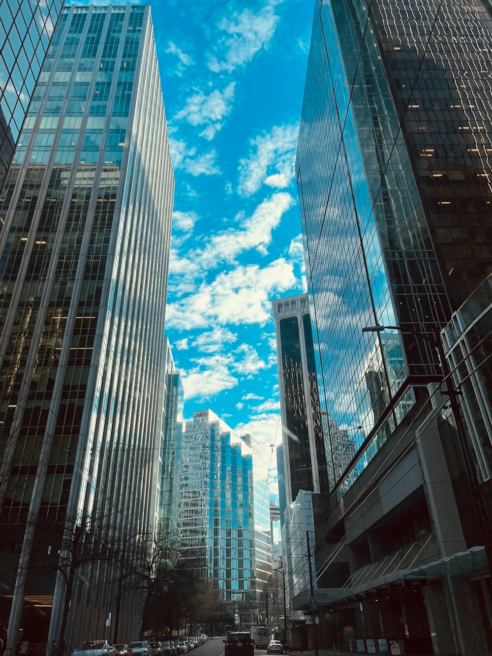 a city street lined with tall buildings under a cloudy blue sky