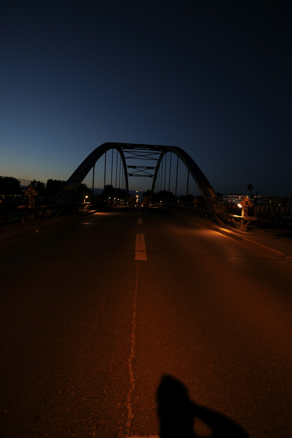 a dark street at night with a bridge in the background