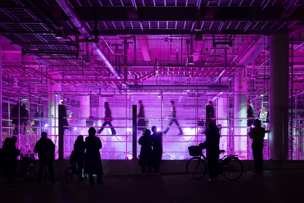 un groupe de personnes debout devant une lumière violette
