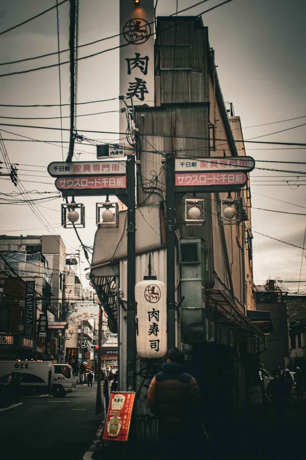 a city street with a tall building with asian writing on it