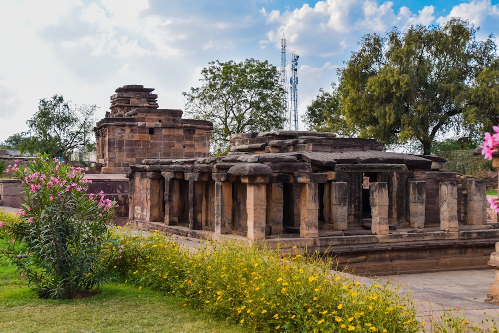 a stone structure surrounded by flowers and trees