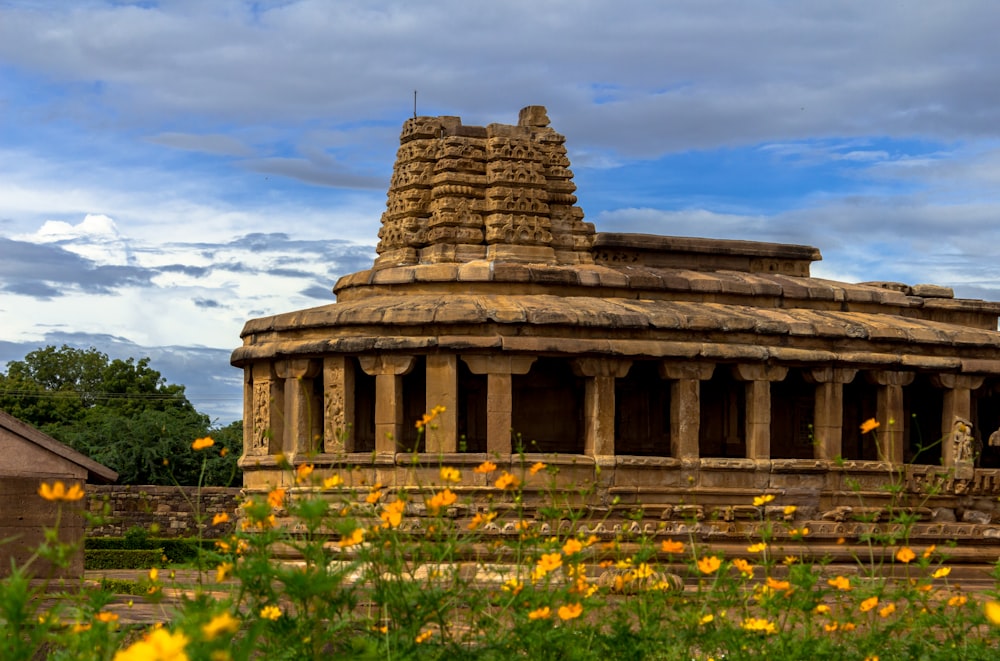 a stone structure with yellow flowers in the foreground