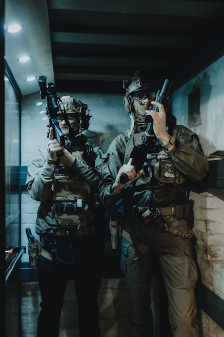 a couple of men standing next to each other holding guns