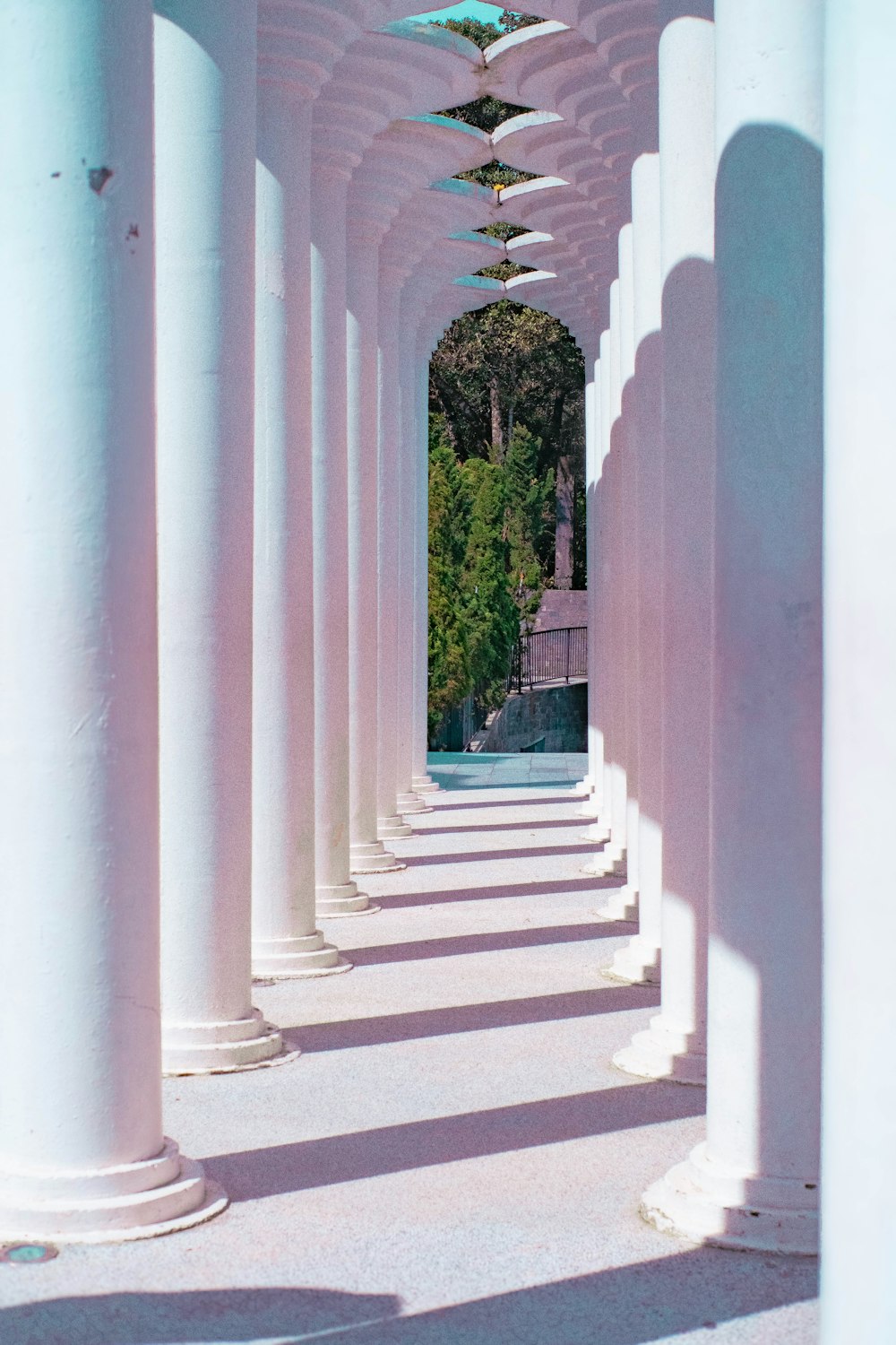 a row of white columns with a blue umbrella hanging from them