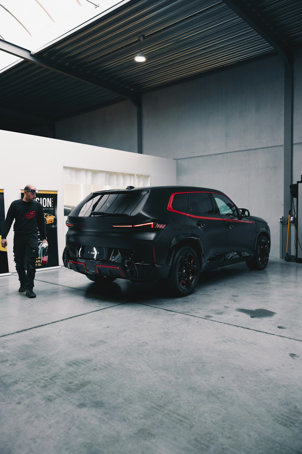 a man standing next to a black car in a garage