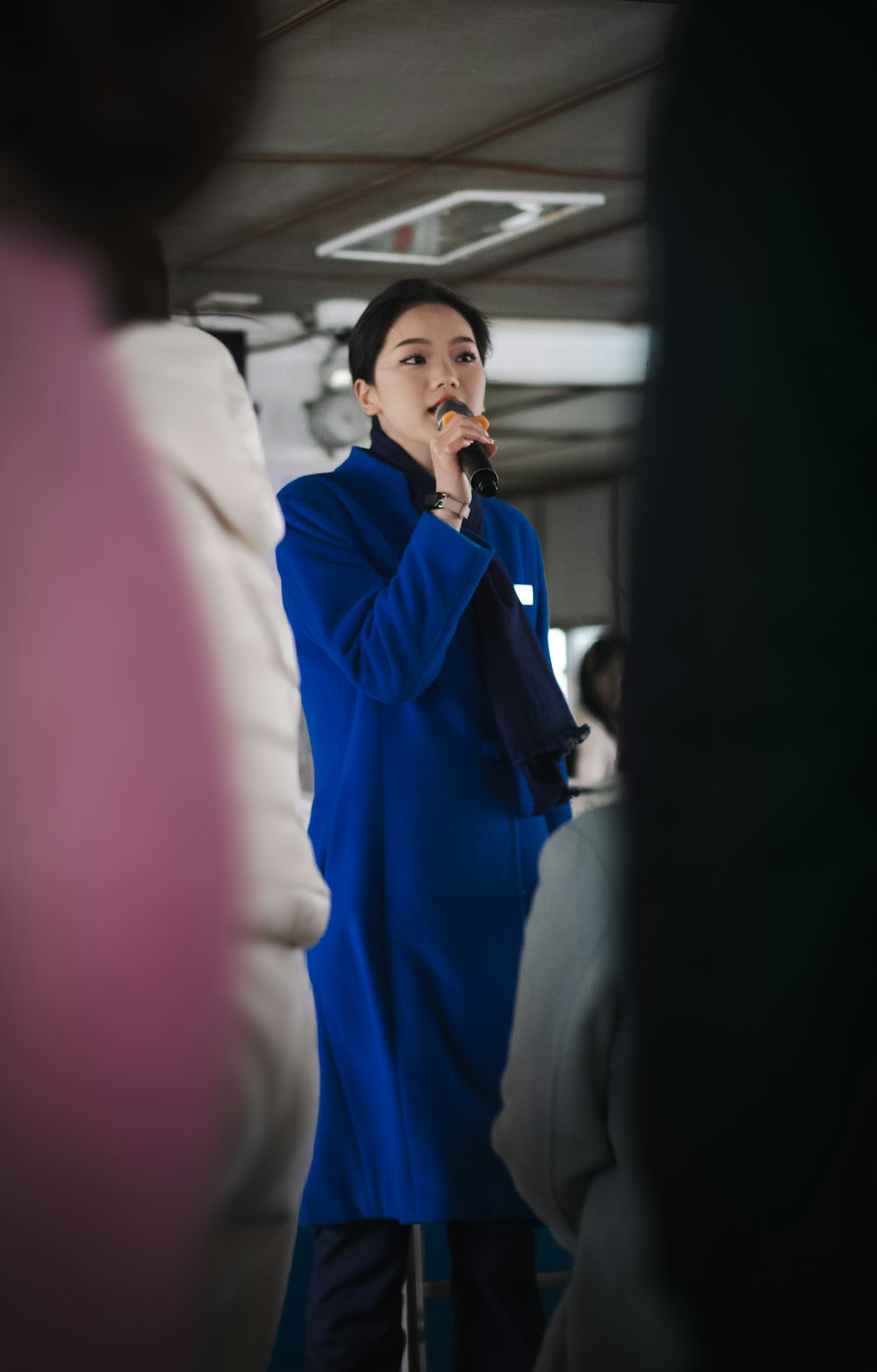 a woman in a blue coat standing in front of a mirror