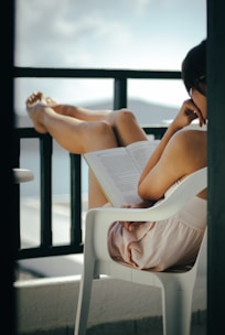 a woman sitting in a chair reading a book