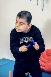 a young boy sitting on a bed holding a toothbrush