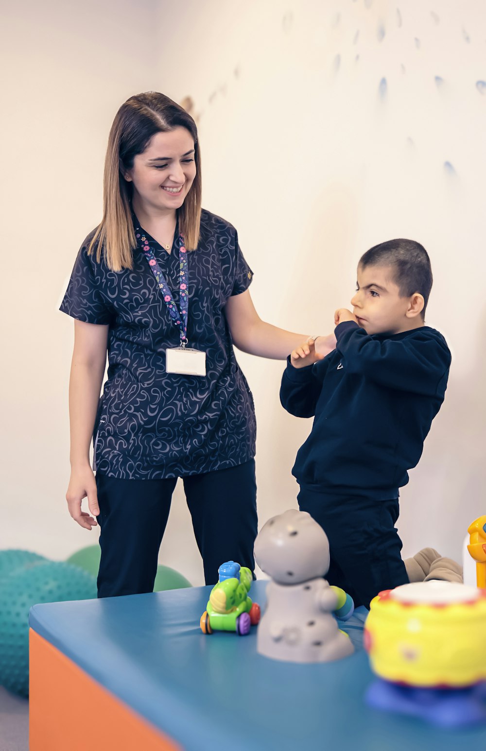 a woman standing next to a boy in a room