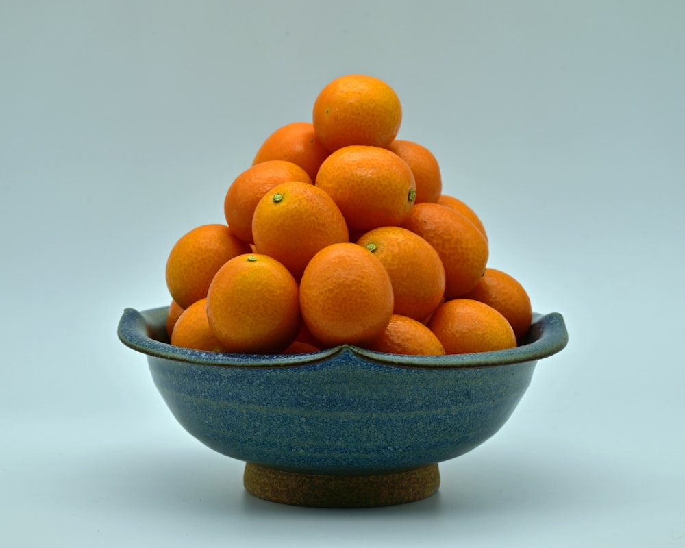 a blue bowl filled with oranges on top of a table