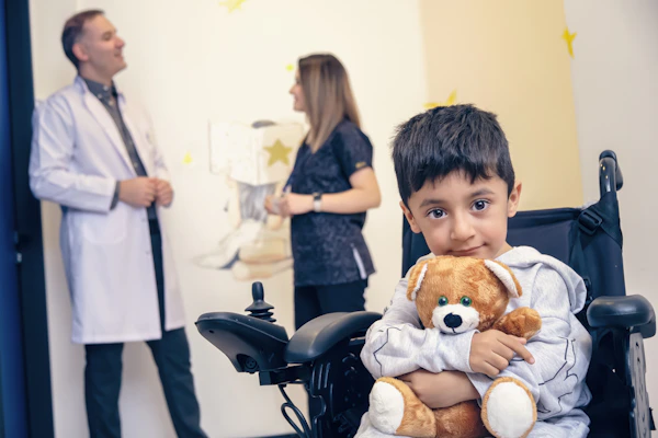 a boy in a wheelchair holding a teddy bear