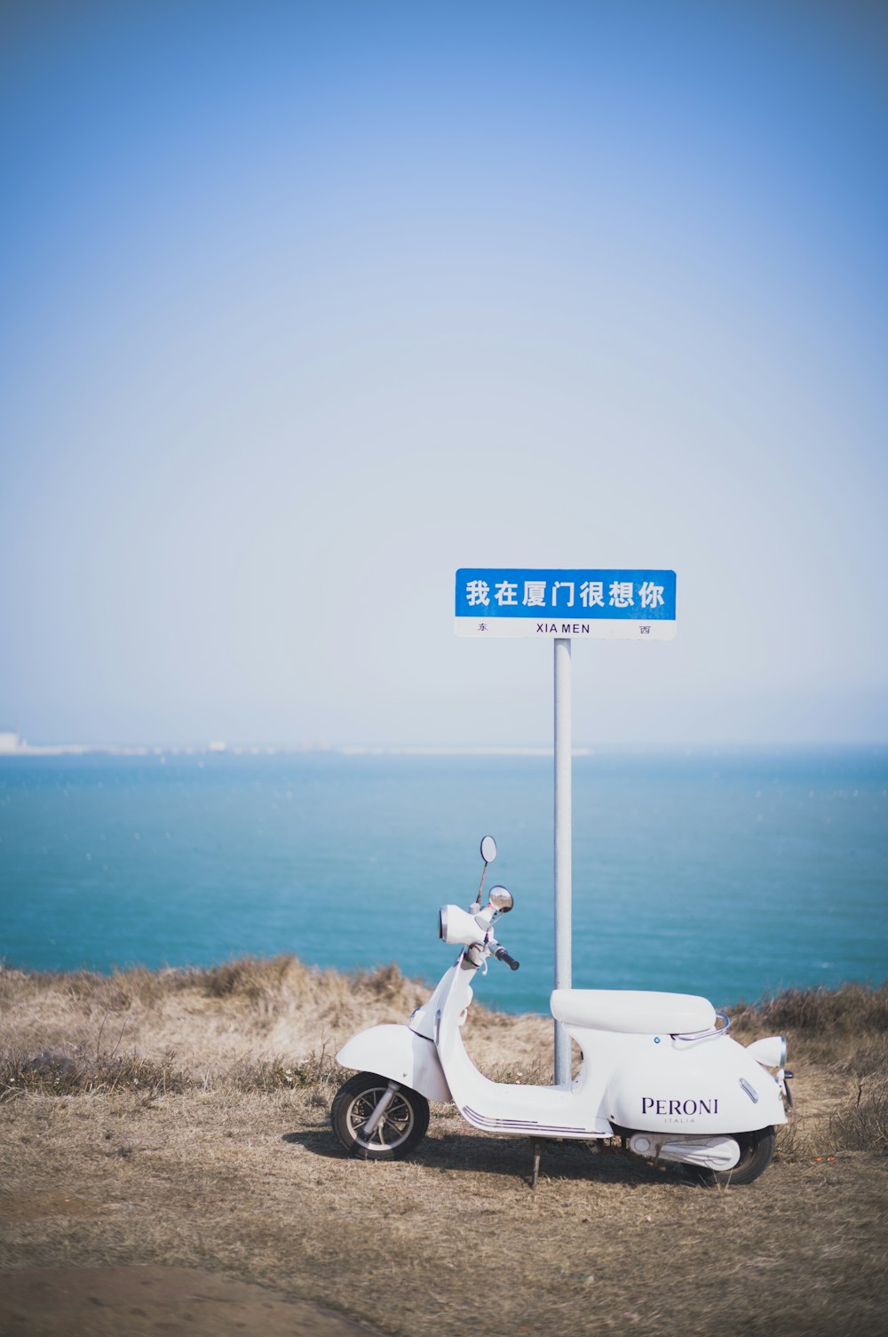 a scooter parked on the side of a road next to the ocean