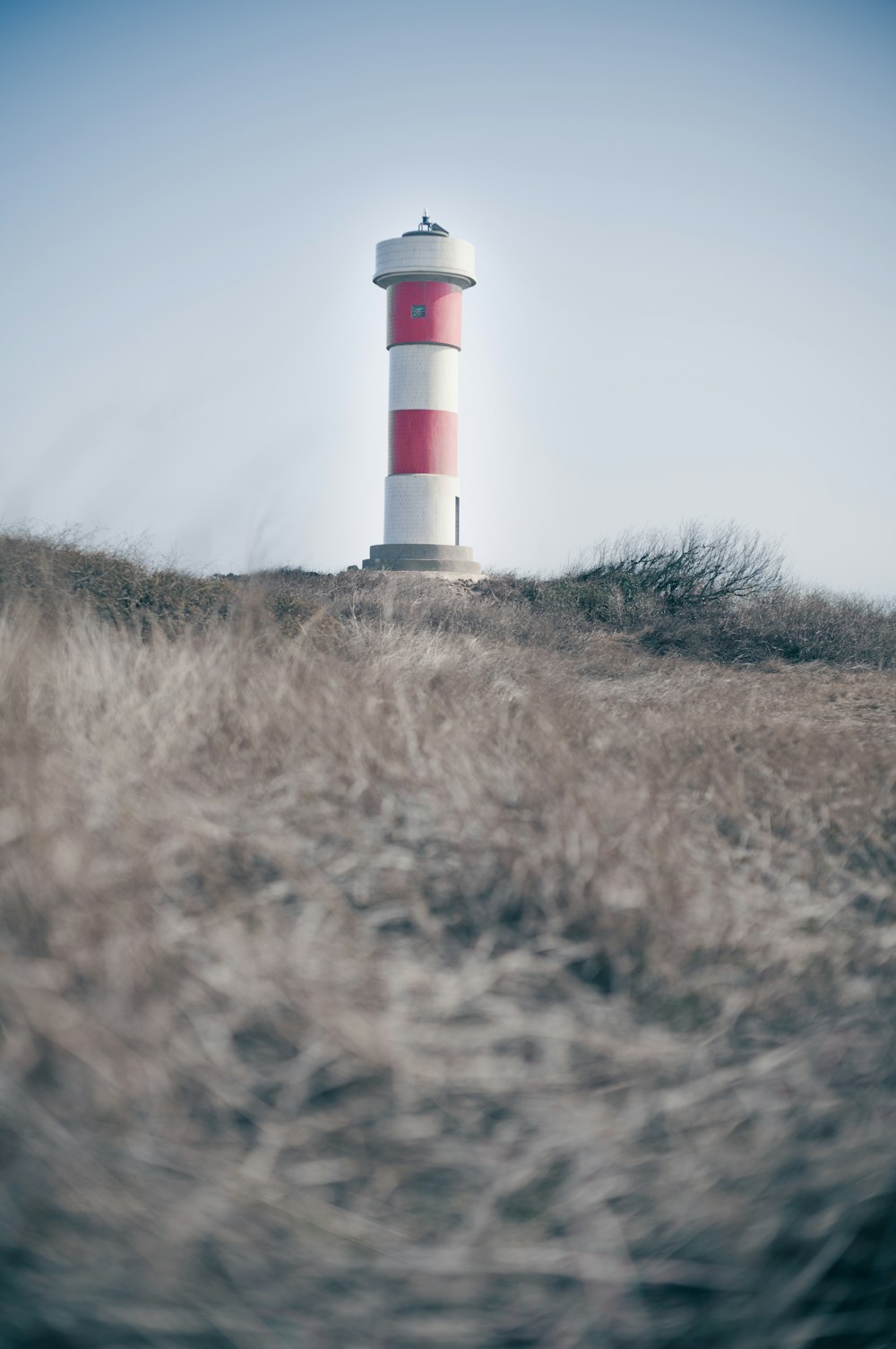 un phare rouge et blanc assis au sommet d’une colline