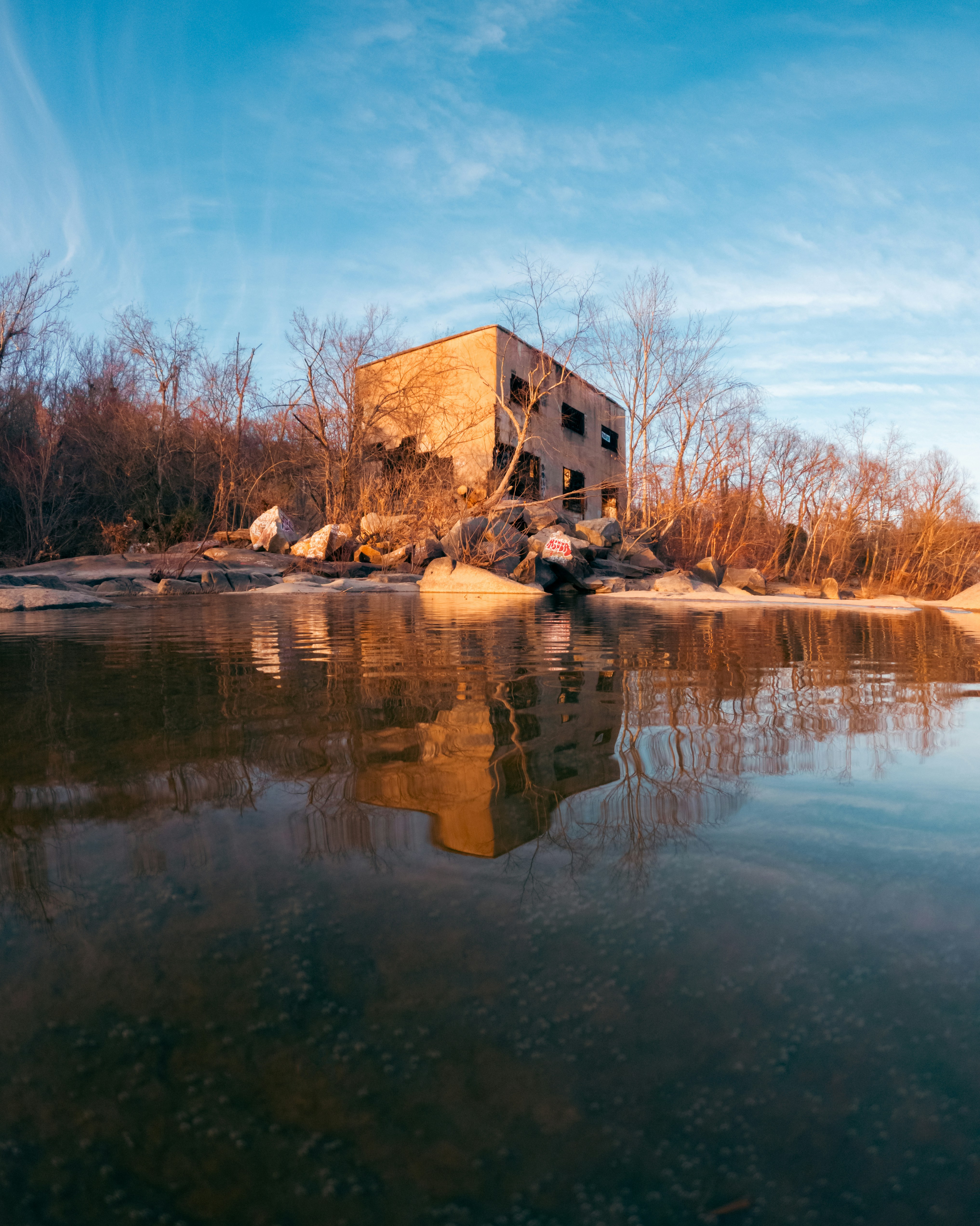 Una casa sentada en la cima de una colina junto a un cuerpo de agua