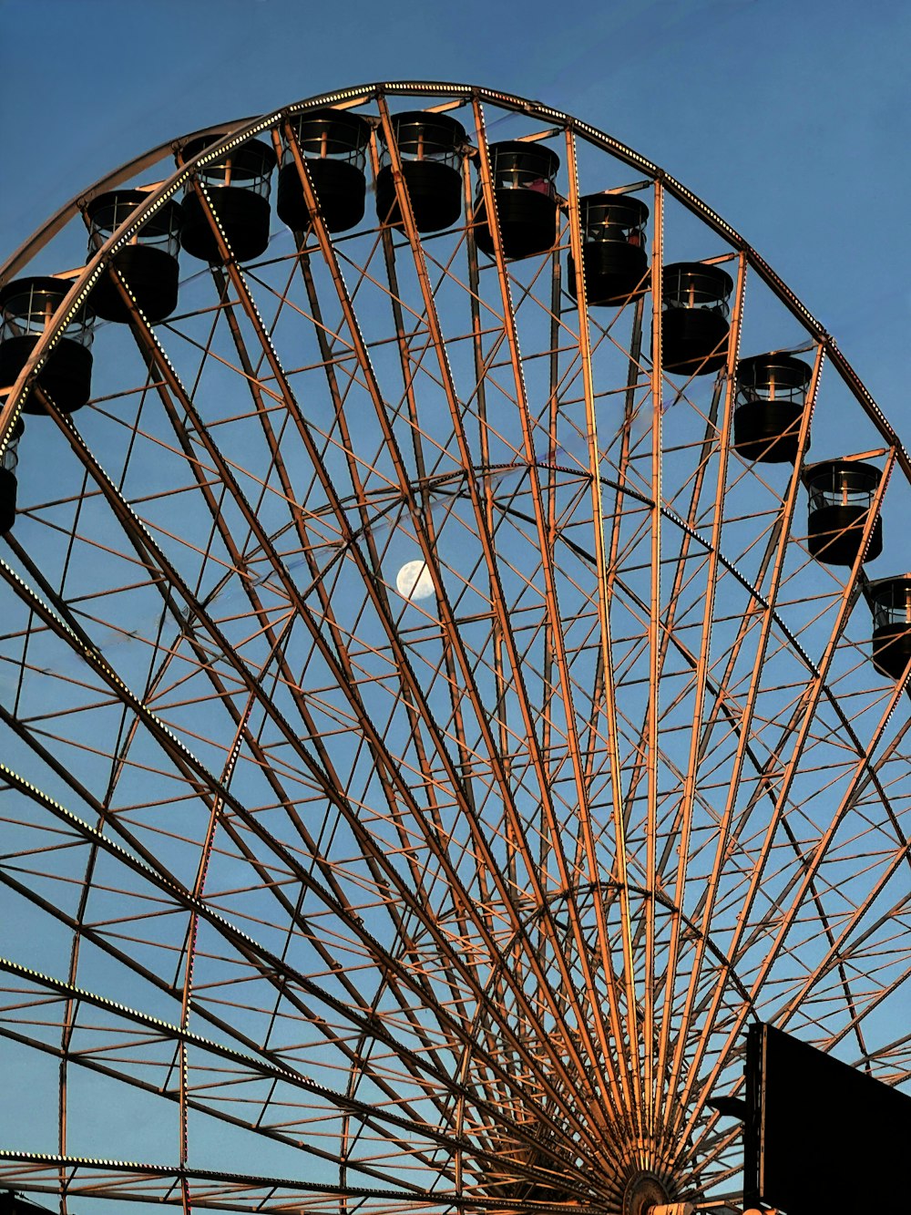 a large ferris wheel with a half moon in the sky