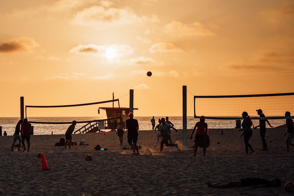 a group of people playing volleyball on the beach