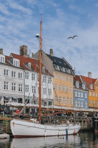 a sailboat docked in a harbor with buildings in the background