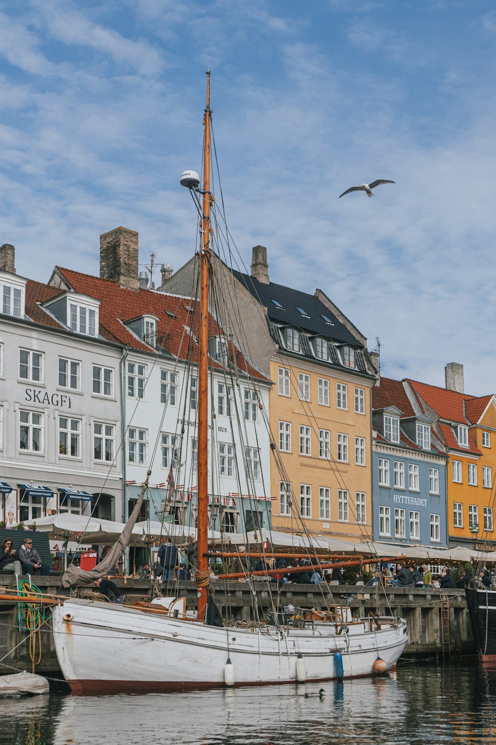 a sailboat docked in a harbor with buildings in the background