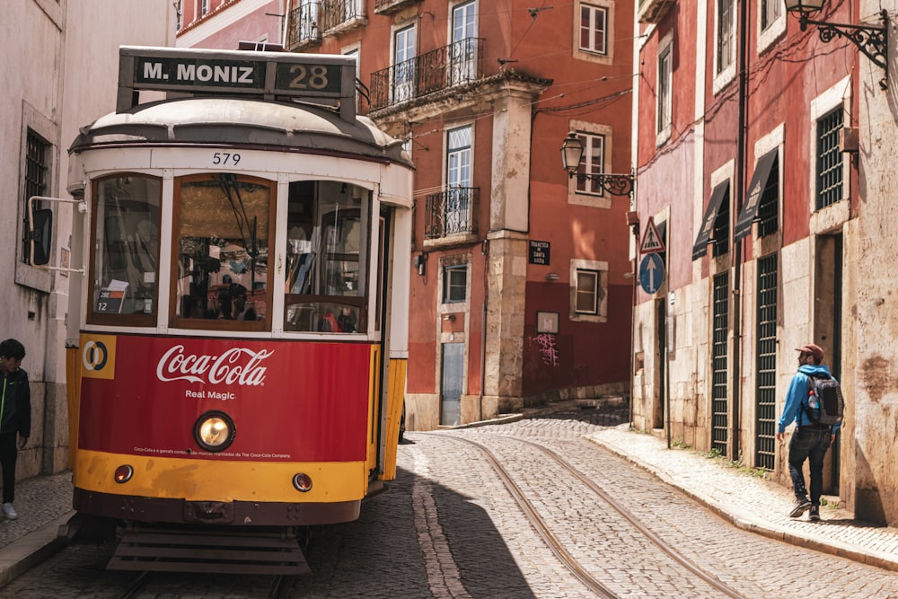 a red and yellow trolley car traveling down a street next to tall buildings